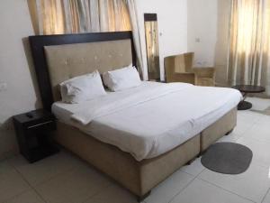 um quarto com uma cama grande com lençóis brancos e almofadas em St Theresers apartments lodge4 em Lagos