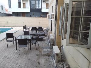 um pátio com uma mesa e cadeiras ao lado de um edifício em St Theresers apartments lodge4 em Lagos