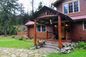 Blockhaus mit einer Veranda und einer Tür in der Unterkunft Idyllic Cabin Getaway with Hot Tub By Titus Mountain in Malone