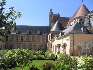 un grand bâtiment avec une cour plantée d'arbres et de plantes dans l'établissement Le Vintage- bords de l'Yonne, à Sens