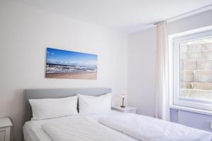 ein weißes Schlafzimmer mit einem Bett und einem Fenster in der Unterkunft Ahrendt- Haus Cäcilia  in Wenningstedt-Braderup