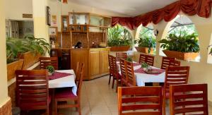 a restaurant with tables and chairs and a kitchen at Sunset Hotel Entebbe in Entebbe