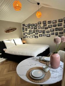 Un dormitorio con una cama y una mesa con platos y flores. en Huisje bij Zee (gratis parkeren), en Noordwijk aan Zee