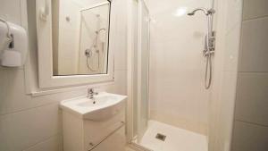 La salle de bains blanche est pourvue d'un lavabo et d'une douche. dans l'établissement Langolo di laura borgo roma destiny home 3, à Vérone