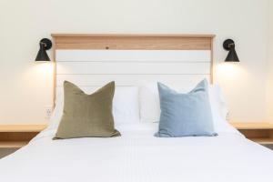 un letto bianco con cuscini e testiera bianca di The Princess Anne 200 Inn at Old Beach a Virginia Beach