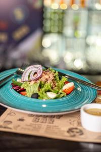 un plato azul con una ensalada en una mesa en IQ Hotel en Kiev