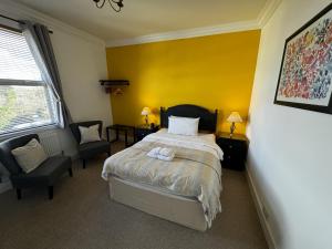 1 dormitorio con cama y pared amarilla en Watermead House, en Chard