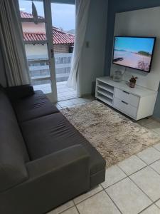 ein Wohnzimmer mit einem Sofa und einem Flachbild-TV in der Unterkunft Edificio Daniela Ap 102 in Bombinhas