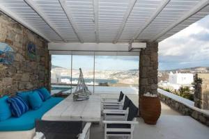 a patio with a table and chairs and a boat at Gorgeous villa w ocean views and shared pools in Ornos