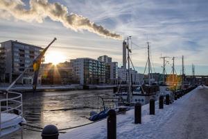 un gruppo di imbarcazioni ormeggiate presso un molo con una pila di fumo di Stylish Studio Haven Ideal for Four Guests a Stoccolma