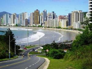 une route en face d'une ville avec une plage et des bâtiments dans l'établissement Ap em Balneário Camboriú, à Balneário Camboriú