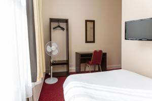 um quarto de hotel com uma cama, uma ventoinha e uma secretária em Islington Inn em Londres