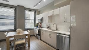 una cucina con armadi bianchi, tavolo e lavandino di Landing Modern Apartment with Amazing Amenities (ID8404X53) a Mobile