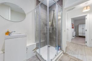 a bathroom with a shower with a sink and a mirror at Luxury Holiday Home near Kings Cross Sleep 12 SP7 in London