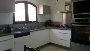 cocina con armarios blancos, fregadero y ventana en Villa Maeva en Toulon