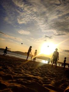 um grupo de pessoas jogando frisbee na praia em Raizes Surf and Bar Hostel em Búzios