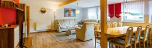 ein Wohnzimmer mit einem Sofa und einem Esstisch in der Unterkunft Hotel & Ferienwohnungen Bohlenblick in Saalfeld