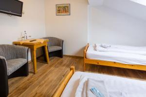 Zimmer mit einem Bett, 2 Stühlen und einem Tisch in der Unterkunft Hotel & Ferienwohnungen Bohlenblick in Saalfeld