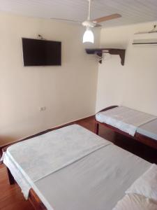 a room with two beds and a flat screen tv at Pousada Estância Mineira in Campo Grande