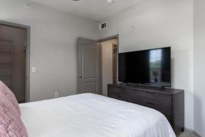een slaapkamer met een bed en een flatscreen-tv bij Landing Modern Apartment with Amazing Amenities (ID4174X27) in Austin