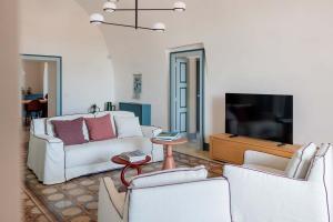 een woonkamer met 2 witte stoelen en een tv bij Tenuta Castione in Polignano a Mare
