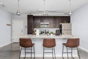 a kitchen with a counter and three bar stools at CozySuites l Dream 1BR, Monument Circle, Indy in Indianapolis