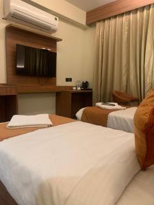 a hotel room with two beds and a television at Hotel Green Lotus By Dsy Hospitality in Noida