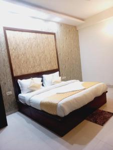 um quarto com uma cama grande com lençóis brancos e almofadas em Hotel Green Lotus By Dsy Hospitality em Noida