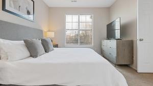 a white bedroom with a large bed and a television at Landing Modern Apartment with Amazing Amenities (ID1981X99) in Greensboro