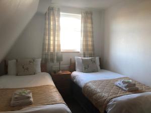 two beds in a small room with a window at Fairways Guest House in Cambridge