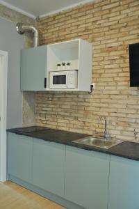 a kitchen with white cabinets and a microwave on a brick wall at La Casa Verde - Ruzafa in Valencia