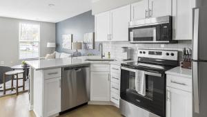 uma cozinha com armários brancos e electrodomésticos pretos em Landing Modern Apartment with Amazing Amenities (ID1263X661) em New Albany