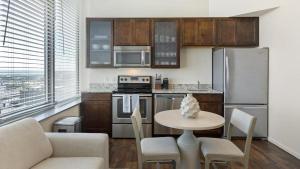 una cocina con mesa y sillas y una cocina con electrodomésticos de acero inoxidable. en Landing Modern Apartment with Amazing Amenities (ID1178X938) en Omaha