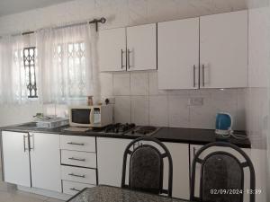 a kitchen with white cabinets and a microwave at PaTerrace guest lodge in Harare