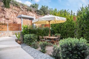 a table and chairs with an umbrella in a garden at La Casa Del Sol Villa in Aegenitissa