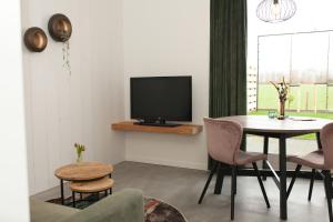 sala de estar con mesa y TV en Het Groeneveld, en Oudkarspel