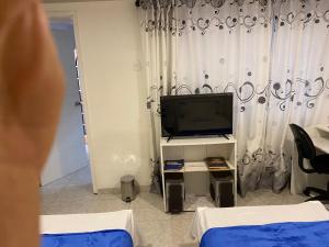 ein Wohnzimmer mit einem TV und ein Zimmer mit 2 Betten in der Unterkunft El apartamento de Mario in Bogotá