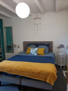 um quarto com uma cama azul e almofadas amarelas em La salamandre de l'escat 