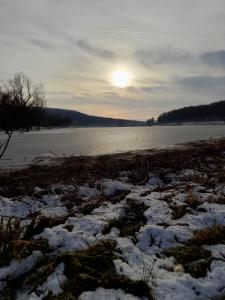 ein schneebedecktes Feld, auf dem die Sonne über dem Wasser aufgeht in der Unterkunft Kasza Rusztika in Szekszárd