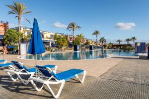 two lounge chairs and an umbrella next to a swimming pool at Meloneras by the sea in San Bartolomé de Tirajana