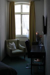ein Wohnzimmer mit einem Stuhl und einem Fenster in der Unterkunft Hotel Restaurant Erbprinz Walldorf in Walldorf