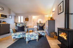 a living room with two chairs and a fireplace at The Tap Room by Big Skies Cottages in Blakeney