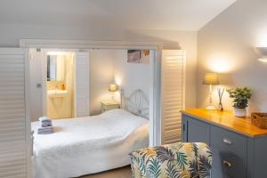 a small bedroom with a bed and a chair at The Tap Room by Big Skies Cottages in Blakeney
