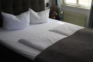 a bed with white sheets and pillows on it at Hotel Restaurant Erbprinz Walldorf in Walldorf