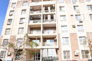 un grand bâtiment avec des balcons et des arbres devant lui dans l'établissement Luxury apartment Madinaty families Only, à Madinaty