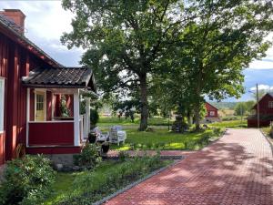 a red house with a porch and a brick driveway at Bärsta Bagarstugan BnB in Kolbäck