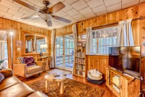 a living room with wooden walls and a ceiling fan at The Cedars Cabin in Welches