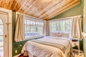 a bed in a room with green walls and windows at The Cedars Cabin in Welches