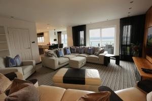una gran sala de estar con sofás y una mesa. en Viewpoint Villa - Luxury 4 Bedroom villa with elevated views, en Rothesay