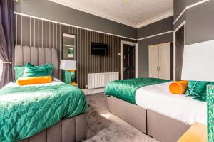 Duas camas num quarto com almofadas verdes e laranja em Room 04 - Sandhaven Rooms Triple em South Shields